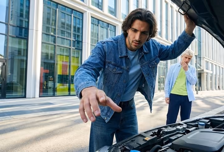 Hombre mirando el capo de su coche roto
