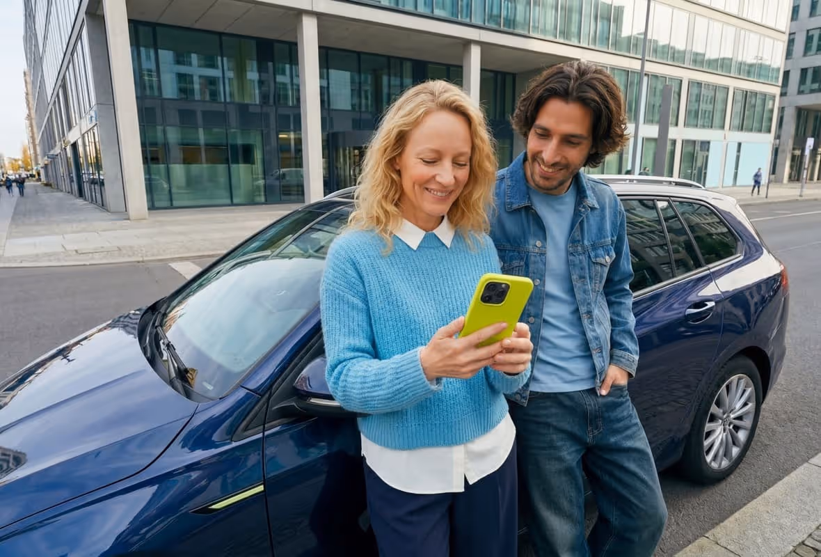 Pareja apoyada en el coche con el móvil